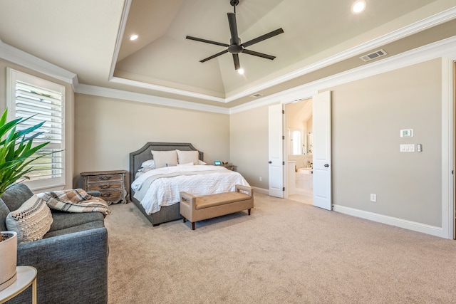 carpeted bedroom with a raised ceiling, vaulted ceiling, ensuite bathroom, ornamental molding, and ceiling fan