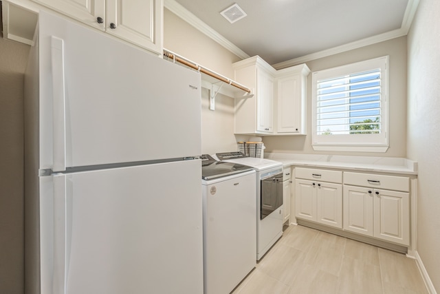 washroom with washing machine and clothes dryer, crown molding, and cabinets