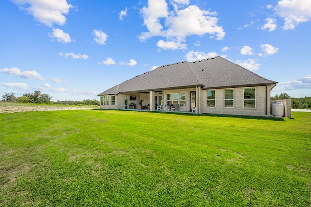 rear view of property with a yard and a patio area