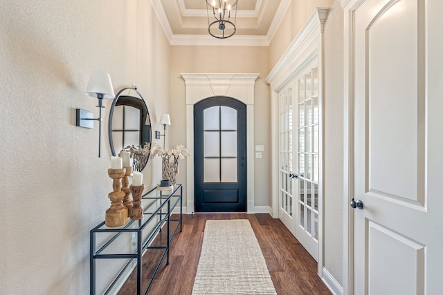 foyer with a chandelier, dark hardwood / wood-style floors, a raised ceiling, and crown molding