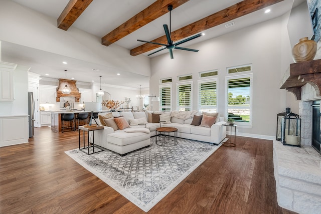 living room with ceiling fan with notable chandelier, dark hardwood / wood-style flooring, and a stone fireplace