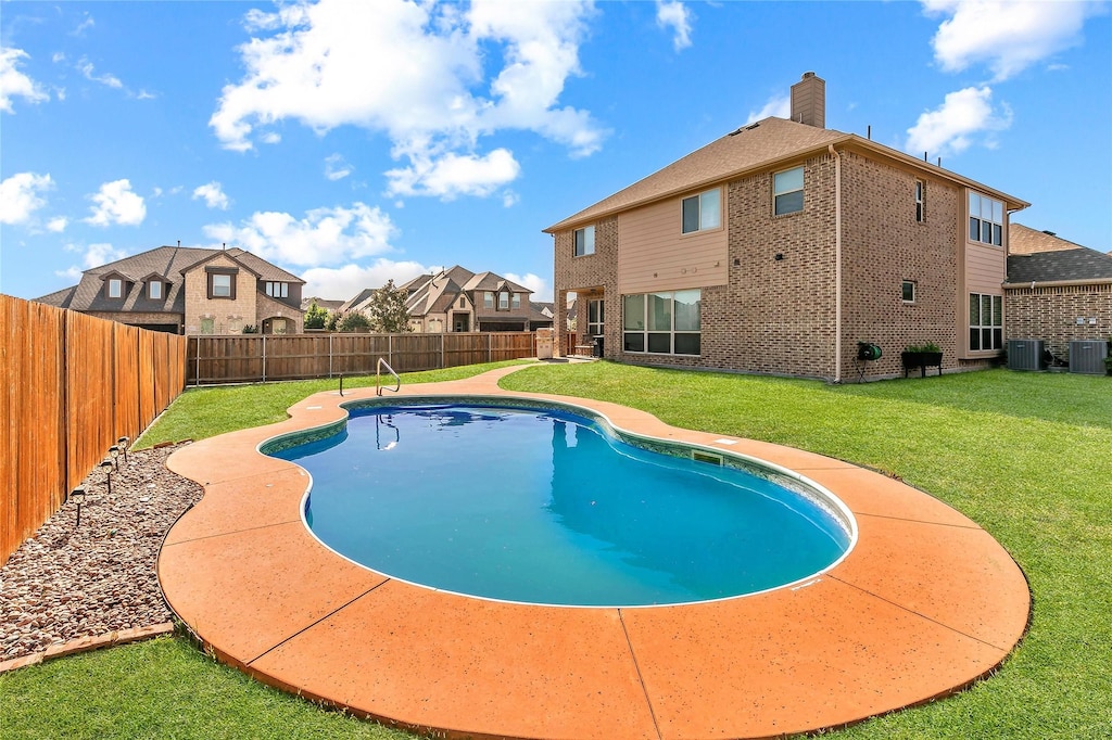 view of swimming pool featuring central air condition unit and a lawn