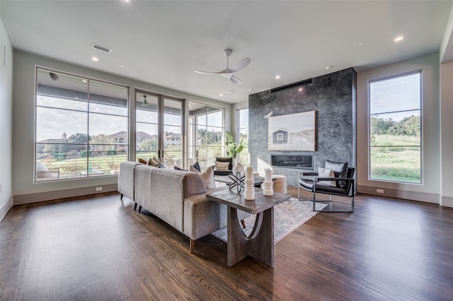 living room featuring ceiling fan, a fireplace, dark hardwood / wood-style floors, and a wealth of natural light