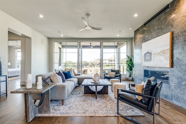 living room featuring hardwood / wood-style flooring, ceiling fan, a premium fireplace, and plenty of natural light