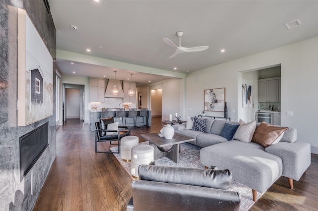 living room with ceiling fan, a fireplace, and dark wood-type flooring