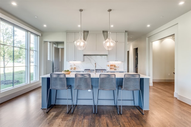 kitchen featuring pendant lighting, wood-type flooring, a large island, and premium range hood