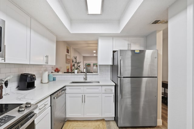 kitchen featuring stainless steel appliances, white cabinets, light hardwood / wood-style floors, and sink