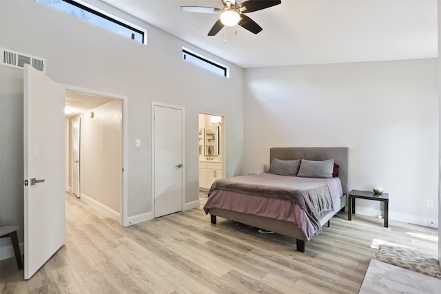 bedroom with light wood-type flooring, connected bathroom, ceiling fan, and high vaulted ceiling