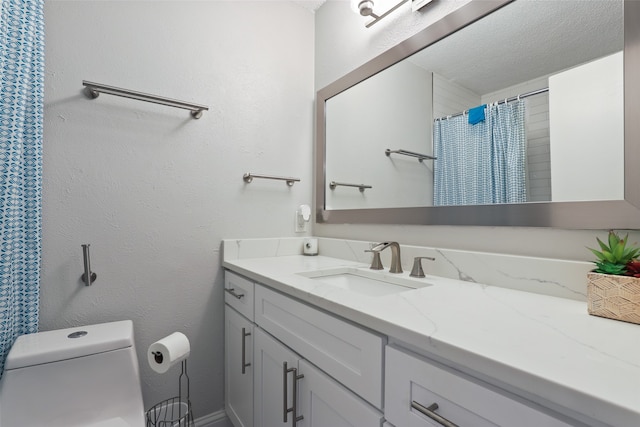 bathroom with a textured ceiling, curtained shower, vanity, and toilet