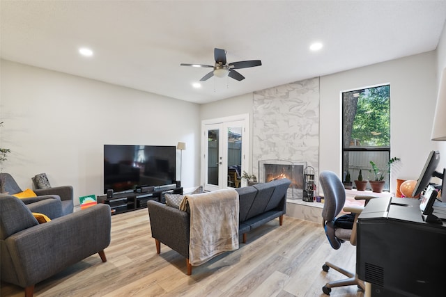 living room featuring light hardwood / wood-style flooring, a high end fireplace, and ceiling fan