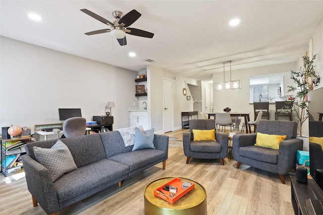 living room with ceiling fan, light hardwood / wood-style flooring, and sink