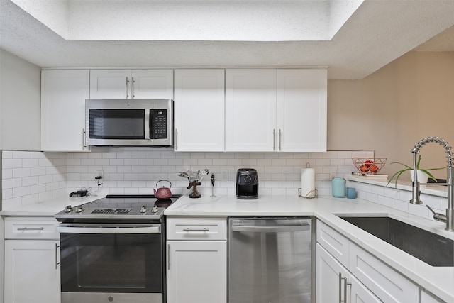 kitchen with appliances with stainless steel finishes, tasteful backsplash, sink, and white cabinets