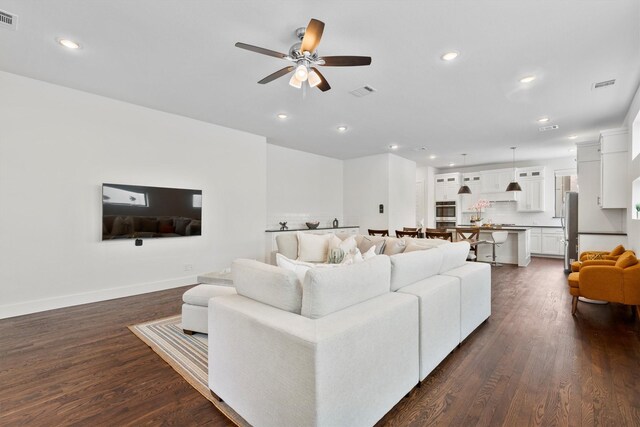 living room featuring ceiling fan and dark hardwood / wood-style flooring