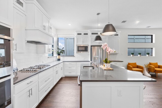 kitchen featuring dark hardwood / wood-style floors, appliances with stainless steel finishes, a kitchen island with sink, sink, and white cabinetry