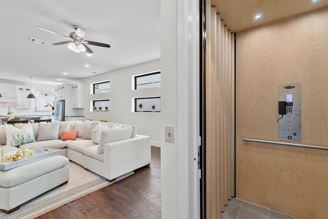 living room featuring ceiling fan, hardwood / wood-style flooring, and elevator