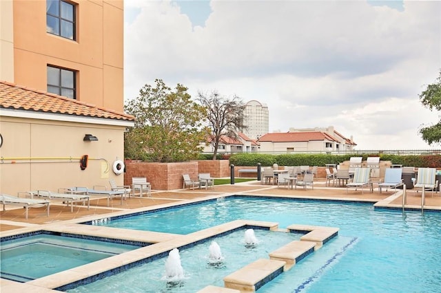 view of swimming pool with a community hot tub, pool water feature, and a patio area