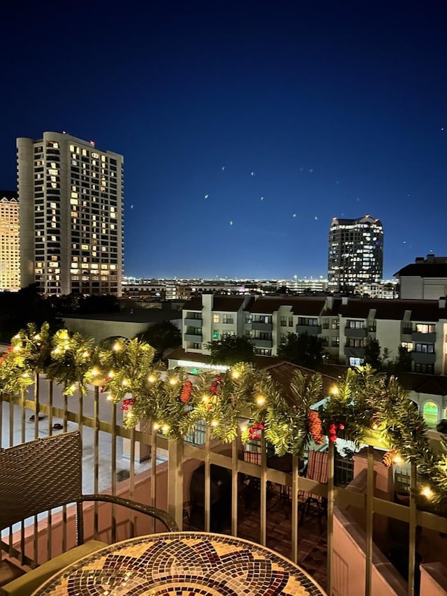 balcony at twilight featuring a view of city lights