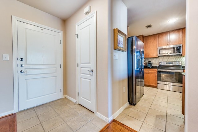 kitchen featuring light tile patterned flooring, appliances with stainless steel finishes, and tasteful backsplash