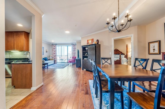 dining space with light hardwood / wood-style flooring, an inviting chandelier, crown molding, and sink