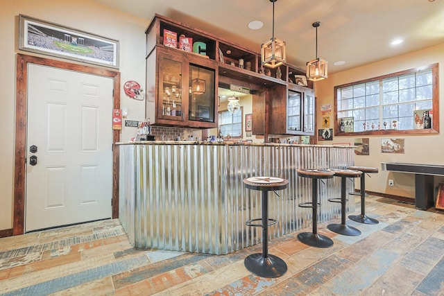 bar with decorative light fixtures, backsplash, and plenty of natural light