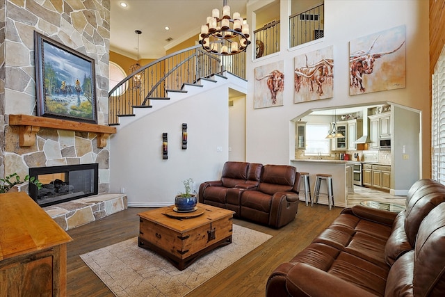 living room featuring plenty of natural light, hardwood / wood-style flooring, a stone fireplace, and a chandelier