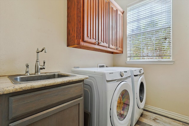 laundry room with light wood-type flooring, cabinets, washer and clothes dryer, and sink