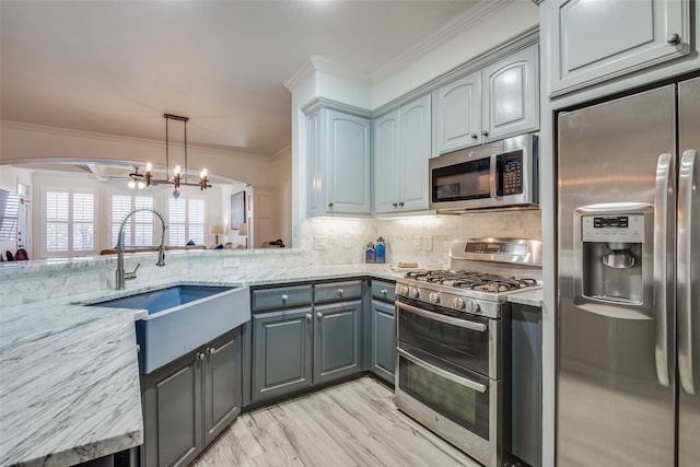 kitchen featuring crown molding, stainless steel appliances, light stone counters, an inviting chandelier, and sink