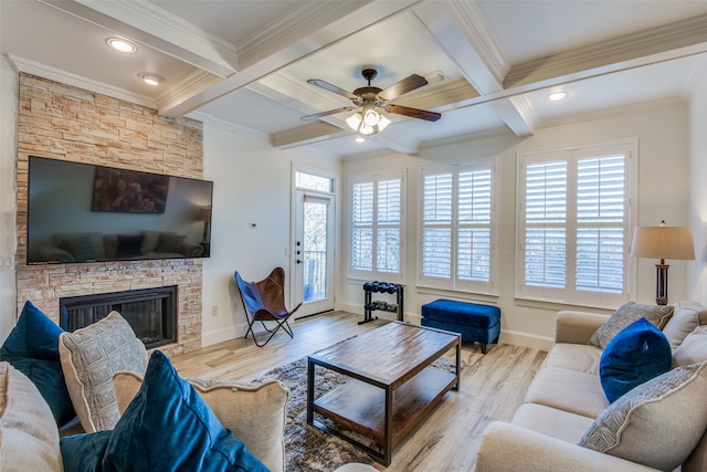 living room featuring light wood-type flooring, a wealth of natural light, ceiling fan, and a stone fireplace