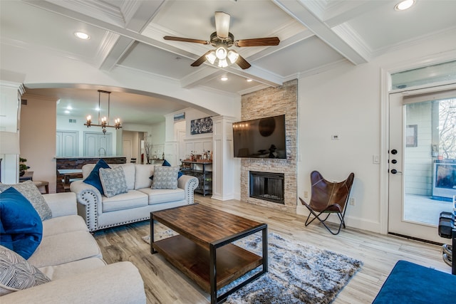 living room featuring a fireplace, light hardwood / wood-style flooring, ceiling fan with notable chandelier, beam ceiling, and ornamental molding