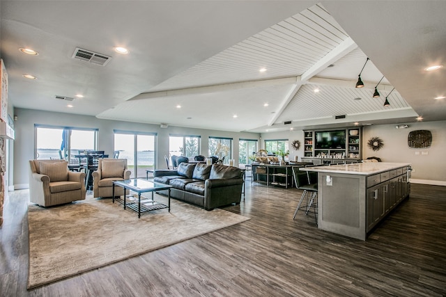 living room with dark wood-type flooring, a healthy amount of sunlight, and vaulted ceiling with beams