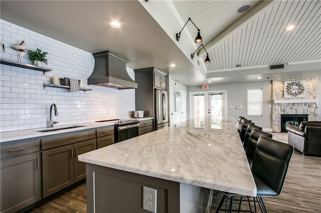 kitchen with a kitchen bar, dark hardwood / wood-style flooring, premium range hood, sink, and appliances with stainless steel finishes