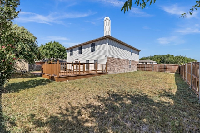 rear view of property with a wooden deck and a lawn