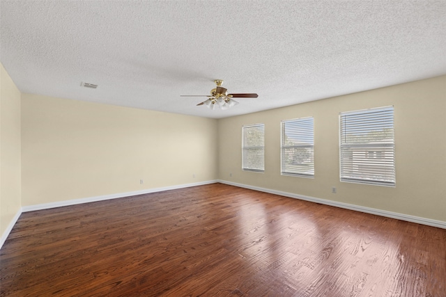 spare room with a textured ceiling, ceiling fan, and dark hardwood / wood-style flooring