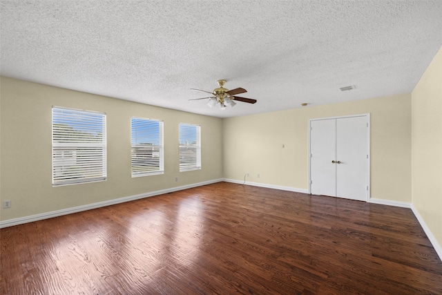 unfurnished room with a textured ceiling, dark hardwood / wood-style floors, and ceiling fan