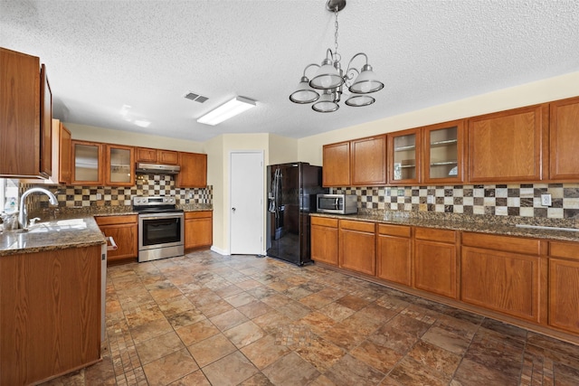 kitchen featuring appliances with stainless steel finishes, decorative light fixtures, tasteful backsplash, sink, and dark stone countertops