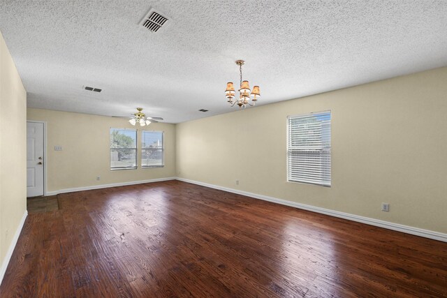 unfurnished room with ceiling fan with notable chandelier, a textured ceiling, and dark wood-type flooring