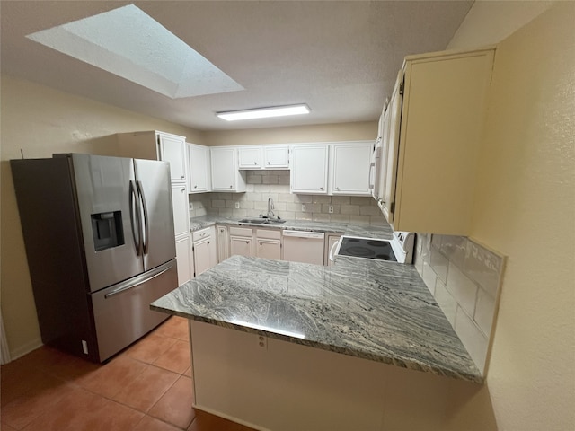 kitchen with white dishwasher, sink, kitchen peninsula, backsplash, and stainless steel refrigerator with ice dispenser