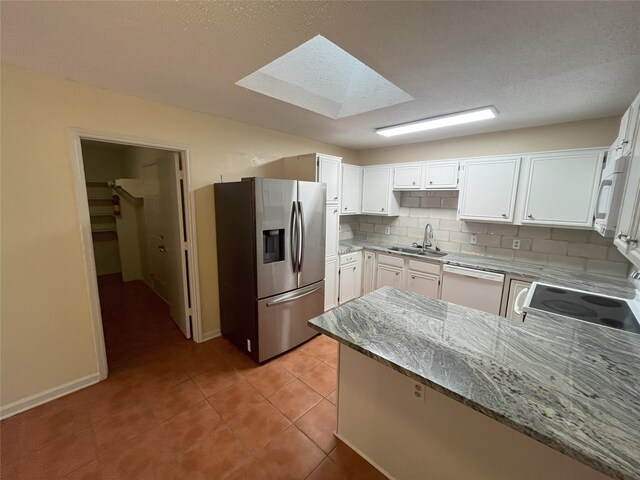 kitchen featuring backsplash, kitchen peninsula, white cabinetry, and stainless steel appliances