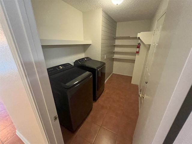 laundry room with a textured ceiling, washing machine and clothes dryer, and tile patterned floors