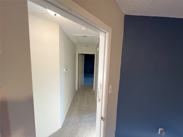 hallway featuring a textured ceiling and light carpet