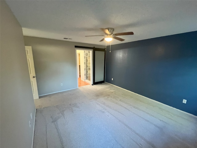 spare room with ceiling fan, a textured ceiling, and light carpet