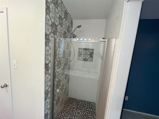 bathroom with a textured ceiling and tiled shower