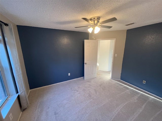 carpeted spare room featuring ceiling fan and a textured ceiling