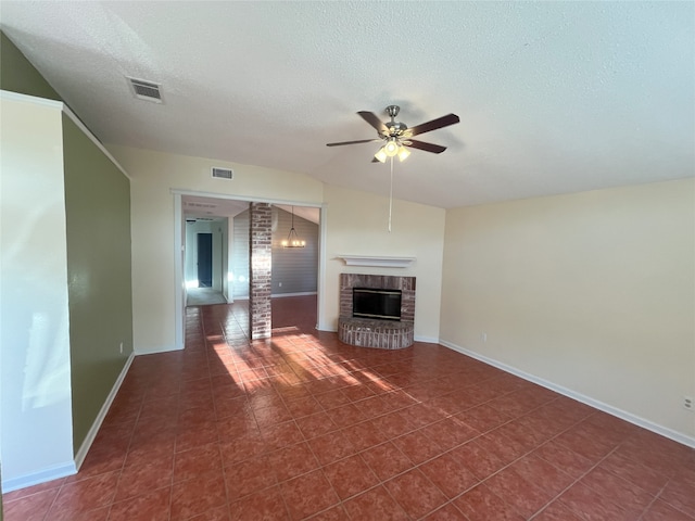 unfurnished living room with dark tile patterned floors, a brick fireplace, ceiling fan, and a textured ceiling