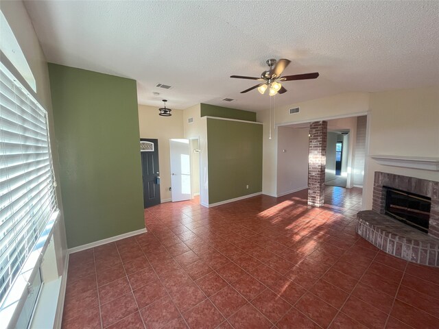 unfurnished living room featuring a textured ceiling, a fireplace, ceiling fan, and dark tile patterned floors