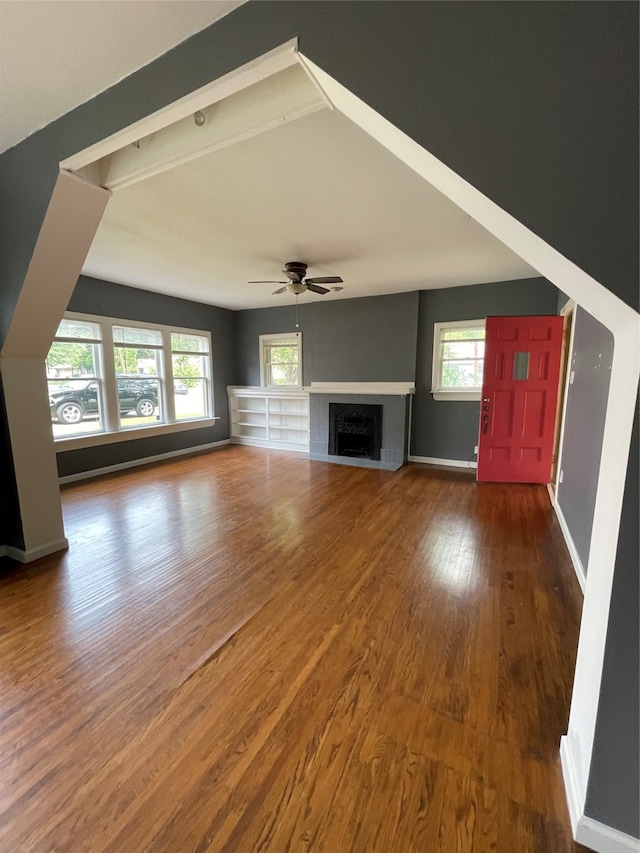 unfurnished living room featuring plenty of natural light, wood-type flooring, and ceiling fan