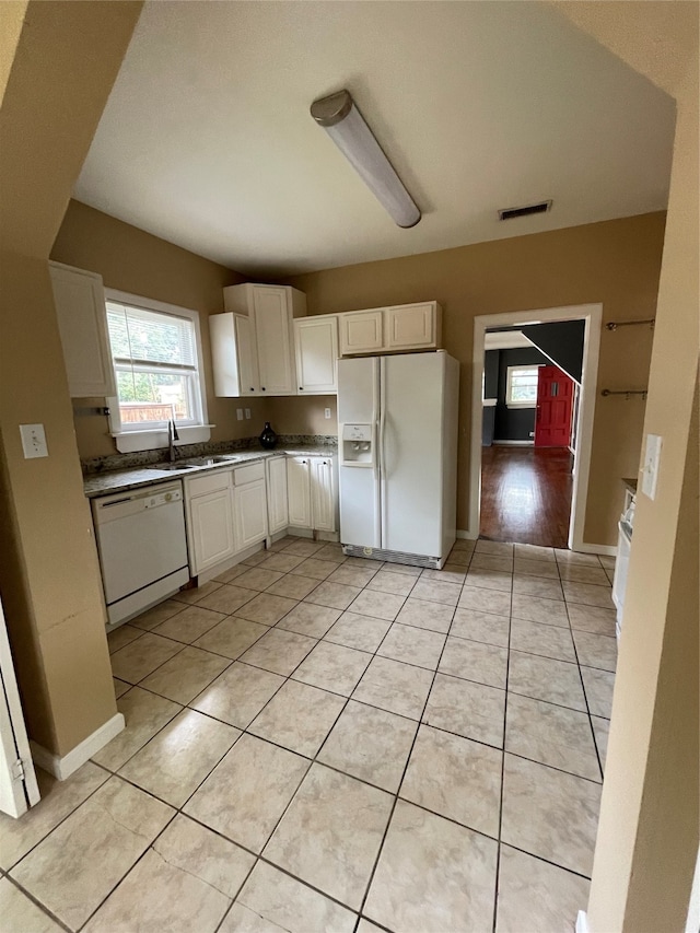 kitchen with white cabinetry, white appliances, light tile patterned floors, and sink