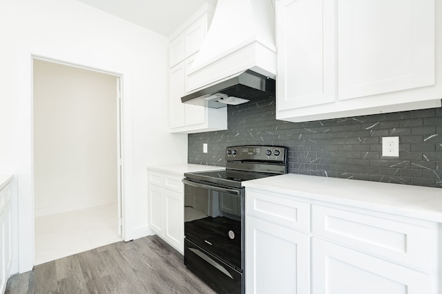 kitchen featuring custom range hood, tasteful backsplash, light hardwood / wood-style floors, white cabinetry, and black electric range oven