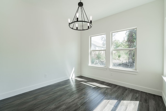 empty room with an inviting chandelier and dark hardwood / wood-style flooring