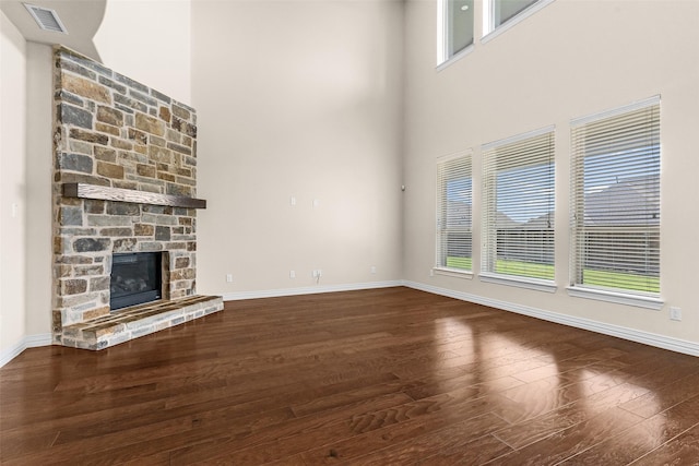 unfurnished living room featuring a stone fireplace, baseboards, visible vents, and wood-type flooring